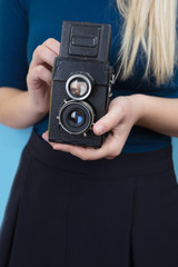 Pretty young girl with retro vintage camera standing and smiling