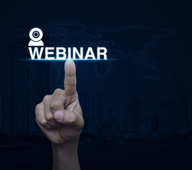 Hand pressing webinar button over world map and city tower, Semi