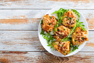 Stuffed chicken breast on white dish with fresh arugula