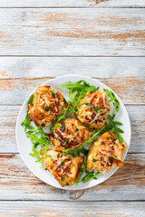 Stuffed chicken breast on white dish with fresh arugula