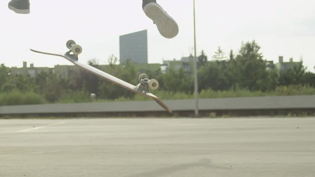 SLOW MOTION CLOSE UP DOF: Skateboarder jumping and doing a flip trick in a city