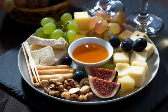 Plate with deli snacks and glasses of wine, closeup