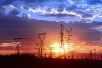 Fototapeta premium Many high voltage towers under the sunset