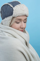 happy young woman in a woolly winter hat with earflaps against b