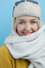 happy young woman in a woolly winter hat with earflaps against b