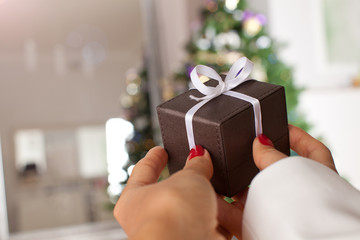Close up shot of female hands holding a small gift box under the