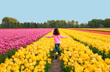 Girl running through flowers fields in Holland