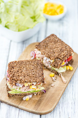 Wooden table with Tuna sandwich (on wholemeal bread; selective f