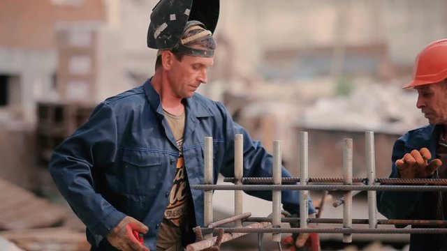 Old builder welding a pipe to the construction