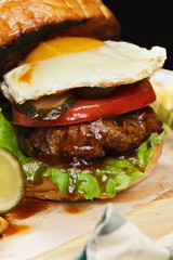 Burger with egg on a wooden board closeup