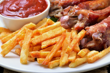Fried potatoes, pork ribs and tomato sauce