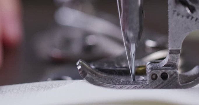 Super slow motion of a professional sewing machine stitching with white thread an Italian haute couture fabric, The seamstress sews a high fashion outfit. concept of industry, tradition, fashion