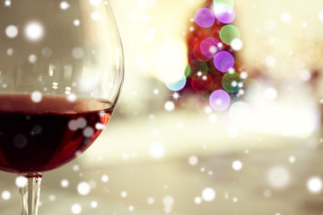 Glass of red wine on blurred festive background, closeup. Christmas celebration concept.