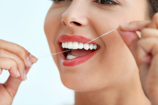 Young woman cleaning teeth with dental floss, close up