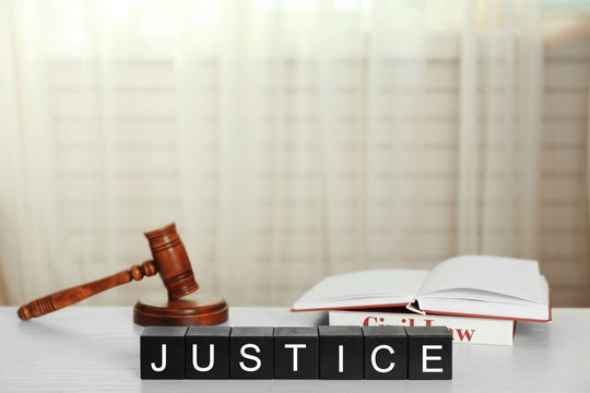 Black cubes with word JUSTICE and gavel on white table