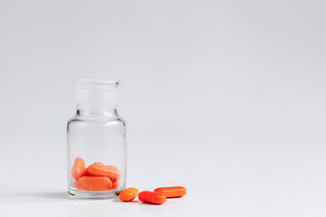 orange pills in glass jar on white background