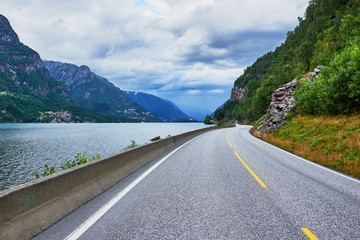 Driving on the middle of the road of highway 13, on the edge of he inlet Sandvevatnet on a cloudy and gray afternoon in Norway