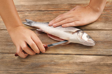 Woman cooking raw fish on kitchen