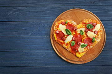 Plate with heart-shaped pizza on wooden background