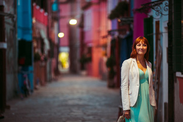Fototapeta premium Lady in mint dress and white jacket walks along an old street