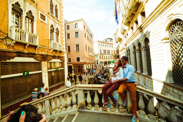 Man and woman sit hugging on the bridge in Venice