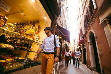 Stylish man in yellow trousers looks at the show-window with tas