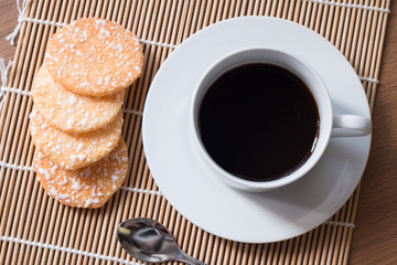 Black coffee in white cup and Crispy Rice Crackers with on woode