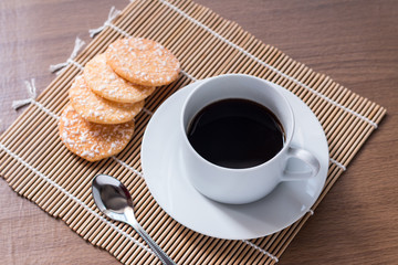 Black coffee in white cup and Crispy Rice Crackers with on woode