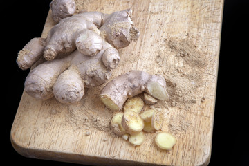 Close up of different forms of ginger against a wood worktop