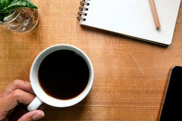 Top view of notebook, pencil, smartphone, cactus and coffee on w