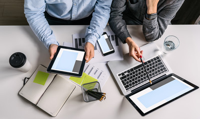 Top view of businessman and businesswoman sitting at white desk and do work together.Businesswoman...