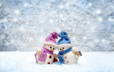 Snowman couple set against each other with snowflakes on the bac