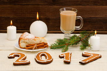 2017 of gingerbread latte mug, candle, apple pie and spruce twigs on a wooden background