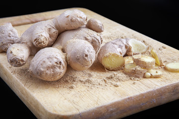 Close up of different forms of ginger against a wood worktop