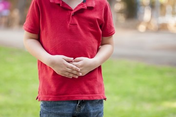 Child with stomach ache, little boy holding hands on his belly.
