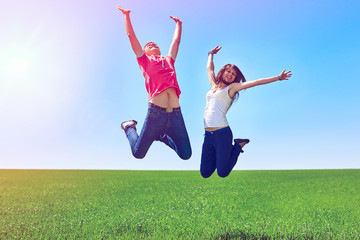 Happy active couple jumping in green field against blue sky