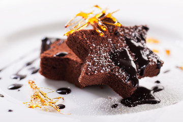 Homemade tasty delicious christmas dessert on a plate - brownie with caramel and chocolate sauce, selective focus