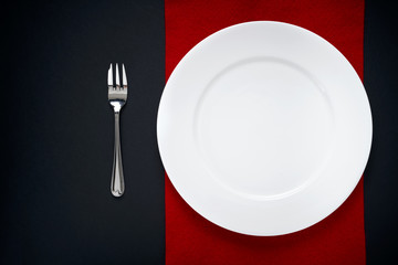 An empty dessert plate on a red mat and black table. Round Plate. 
