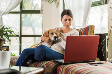 woman relaxing on the sofa with her dog and using tablet