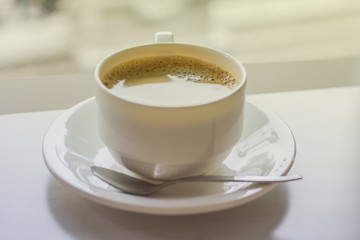 Cup of coffee on a wooden table and in coffee shop.