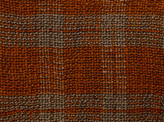 Textured background closeup. Knitted fabric brown in a cage.