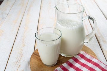 Obraz na płótnie Canvas fresh milk in glass jug and glass on wooden background
