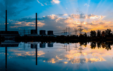 Coal power plant at sunset and reflection in water.