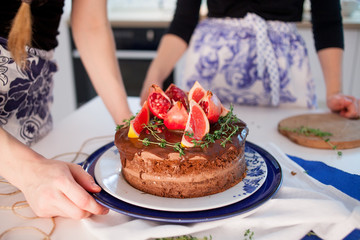 Two girls making a cake on the kitchen. Beautiful cake with cream and decoration of grapefruit and pomegranate