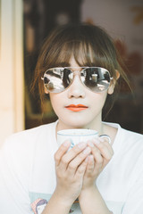Asian woman relaxing on couch with coffee at home in the living room