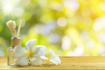 Bottle-conditioned with plumeria on the wooden floor with the beautiful green nature background.