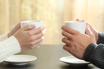 Hands of couple with coffee cups