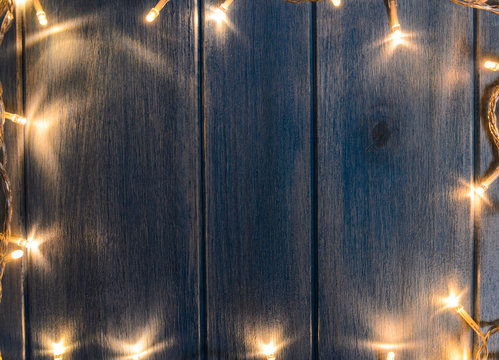 Christmas lights on blue wooden table, view from above