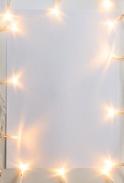 Christmas Lights On Gray Table With Paper Sheet, View From Above