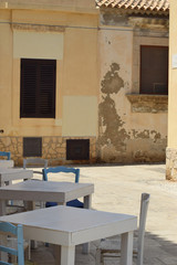 Empty Sicilian street with street cafes and colorful tables